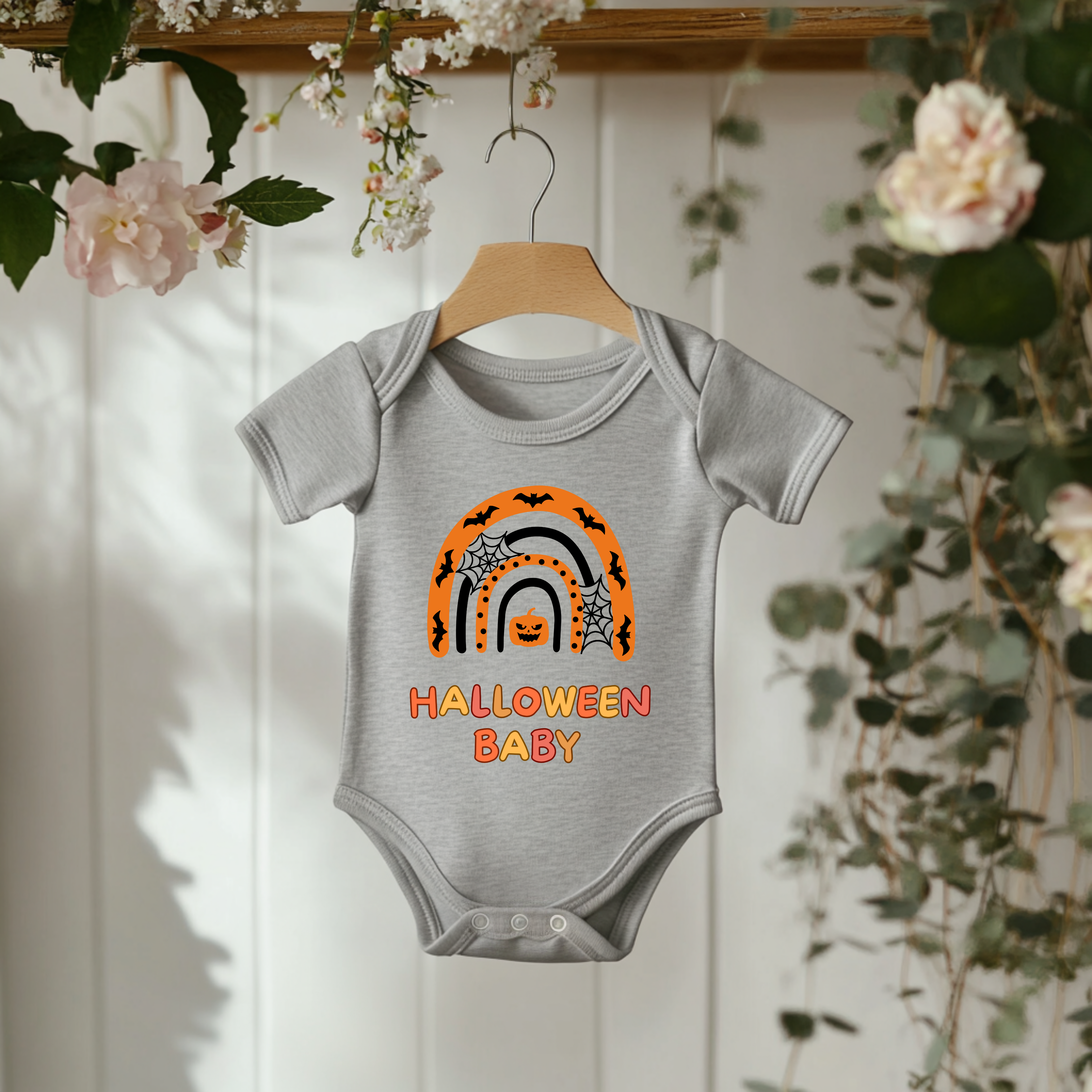 Grauer Baby-Strampler mit Halloween-Motiv: bunter Regenbogen in Orange- und Schwarztönen, darunter der Schriftzug ‚Halloween Baby‘.