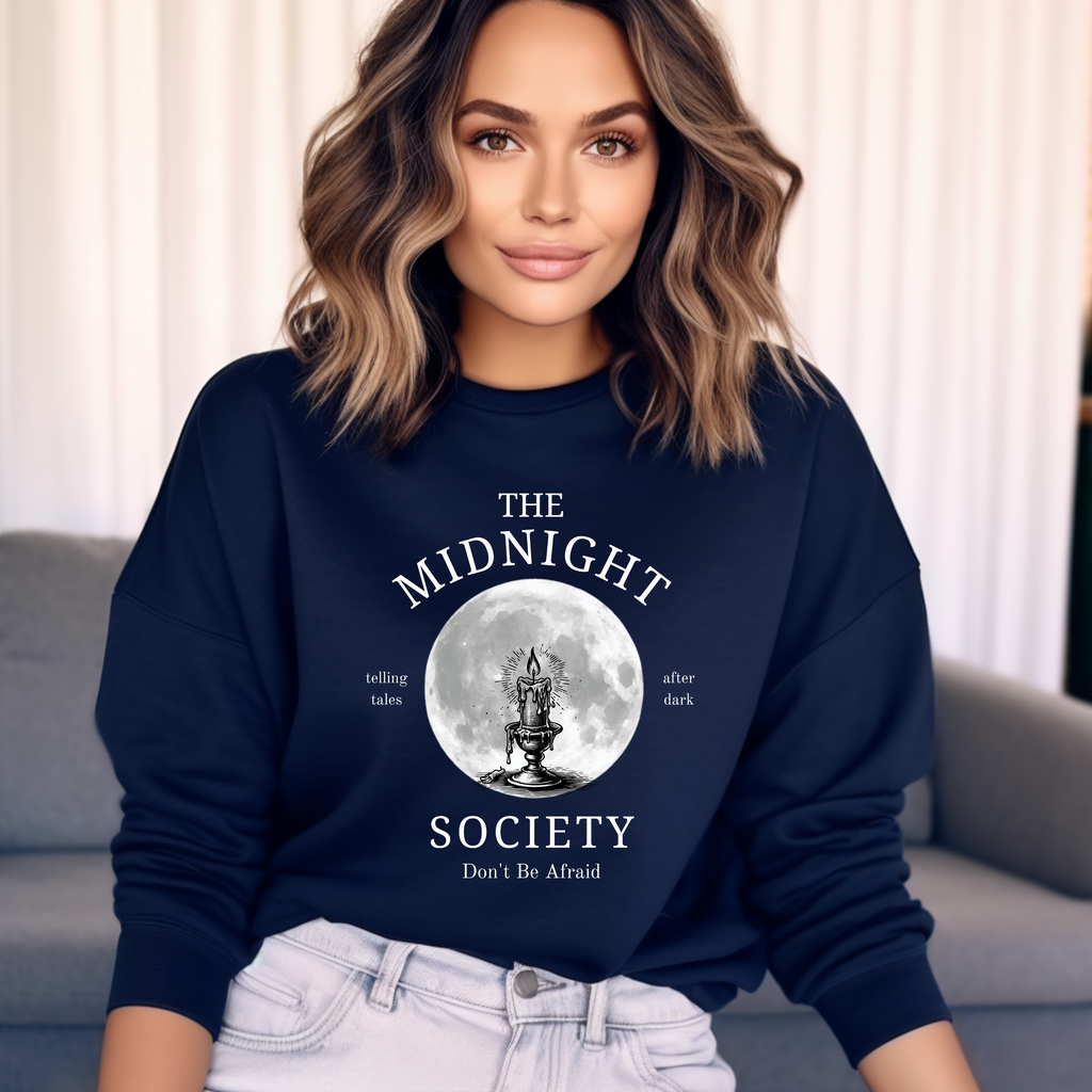 Dunkelblaues Halloween-Sweatshirt mit mystischem Motiv: Eine brennende Kerze im Lineart-Stil vor einem großen Vollmond, darunter der Schriftzug ‚THE MIDNIGHT SOCIETY – telling tales, after dark‘. Design mit Retro- und Gruselflair.
