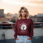 Granatfarbenes Halloween-Sweatshirt mit mystischem Motiv: Eine brennende Kerze im Lineart-Stil vor einem großen Vollmond, darunter der Schriftzug ‚THE MIDNIGHT SOCIETY – telling tales, after dark‘. Design mit Retro- und Gruselflair.
