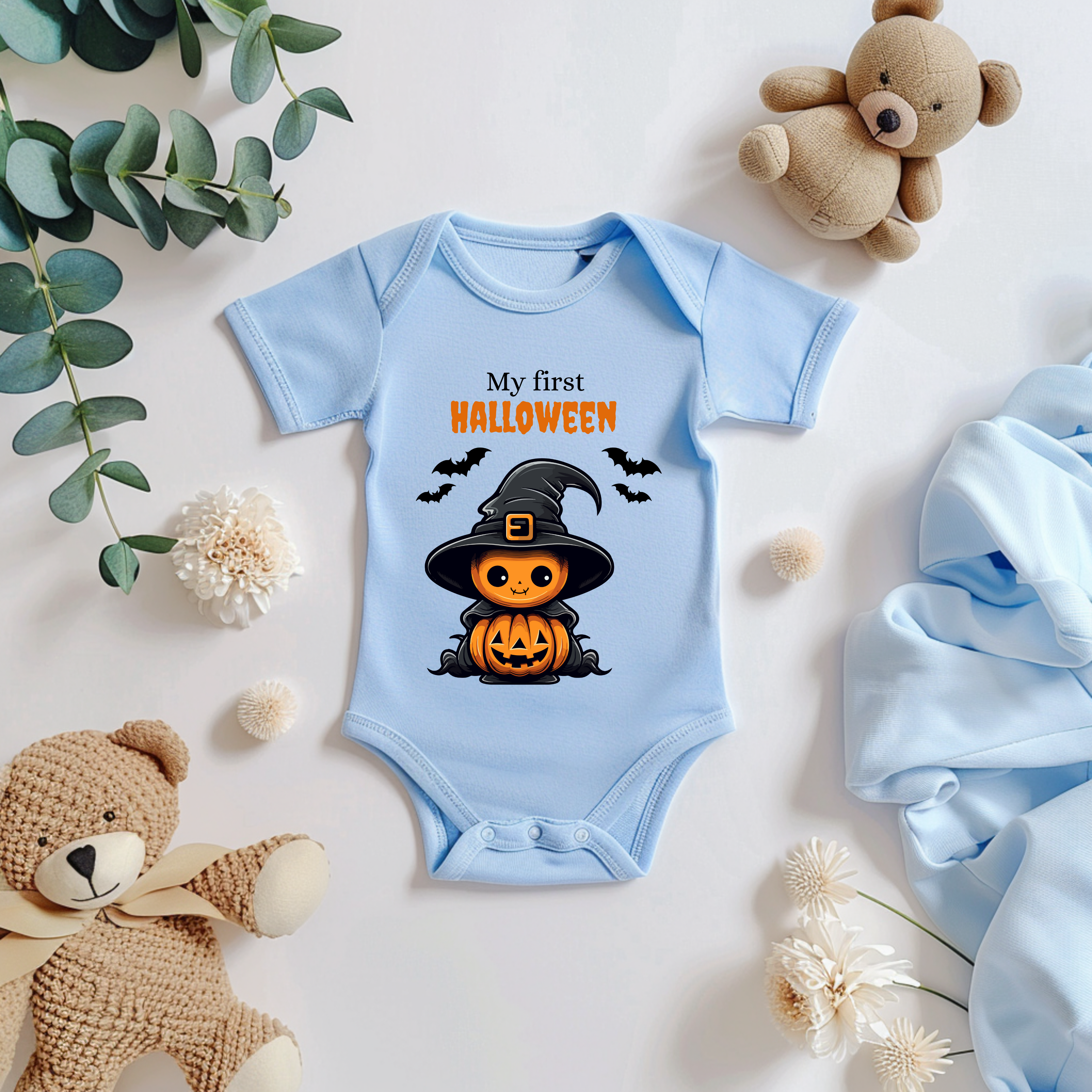 Hellblauer Baby-Strampler mit Halloween-Motiv: niedlicher Kürbis im Hexenkostüm mit Hut und Umhang, umgeben von Fledermäusen. Darüber der Schriftzug ‚My First Halloween‘.
