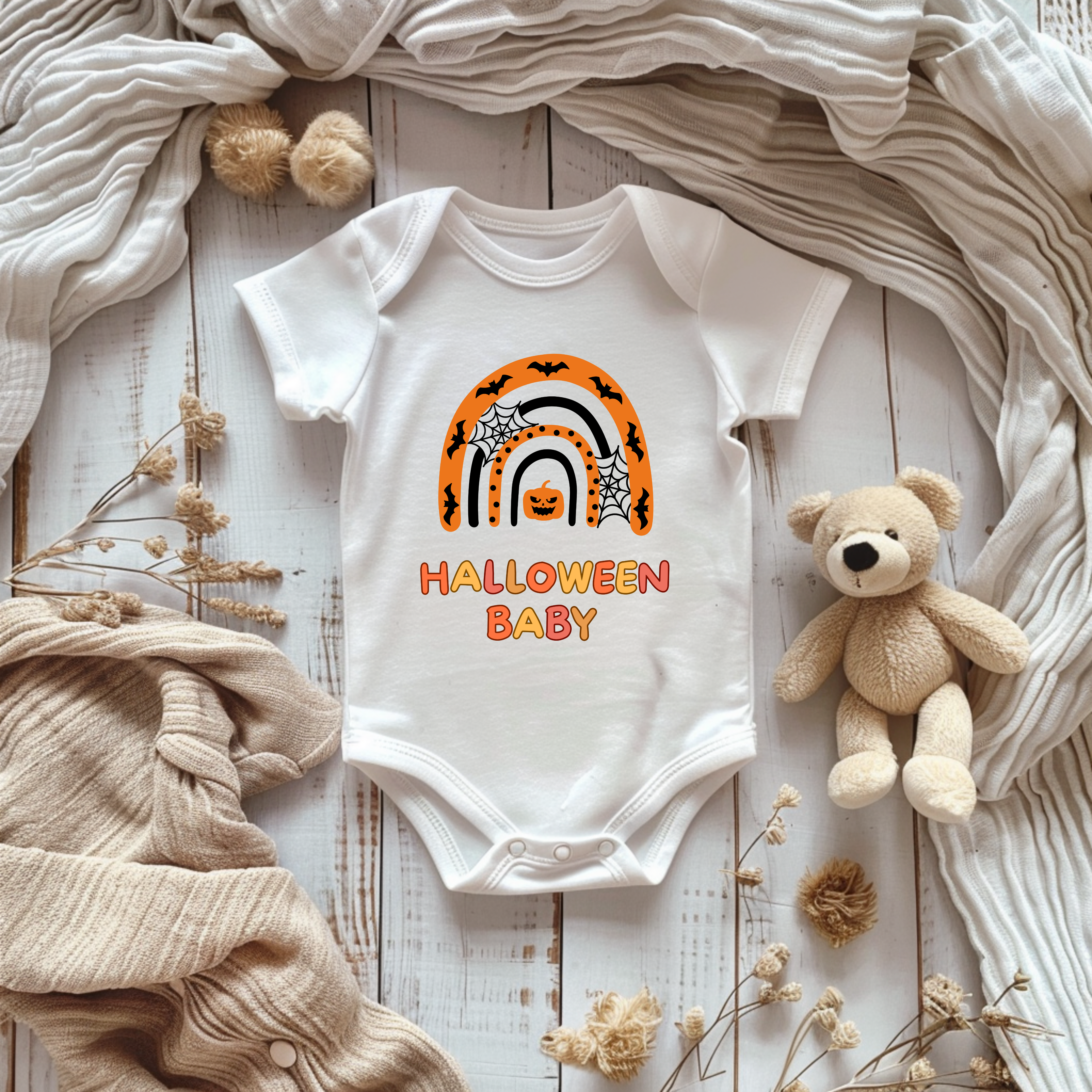 Weißer Kurzarm Baby-Strampler mit Halloween-Motiv: bunter Regenbogen in Orange- und Schwarztönen, darunter der Schriftzug ‚Halloween Baby‘.