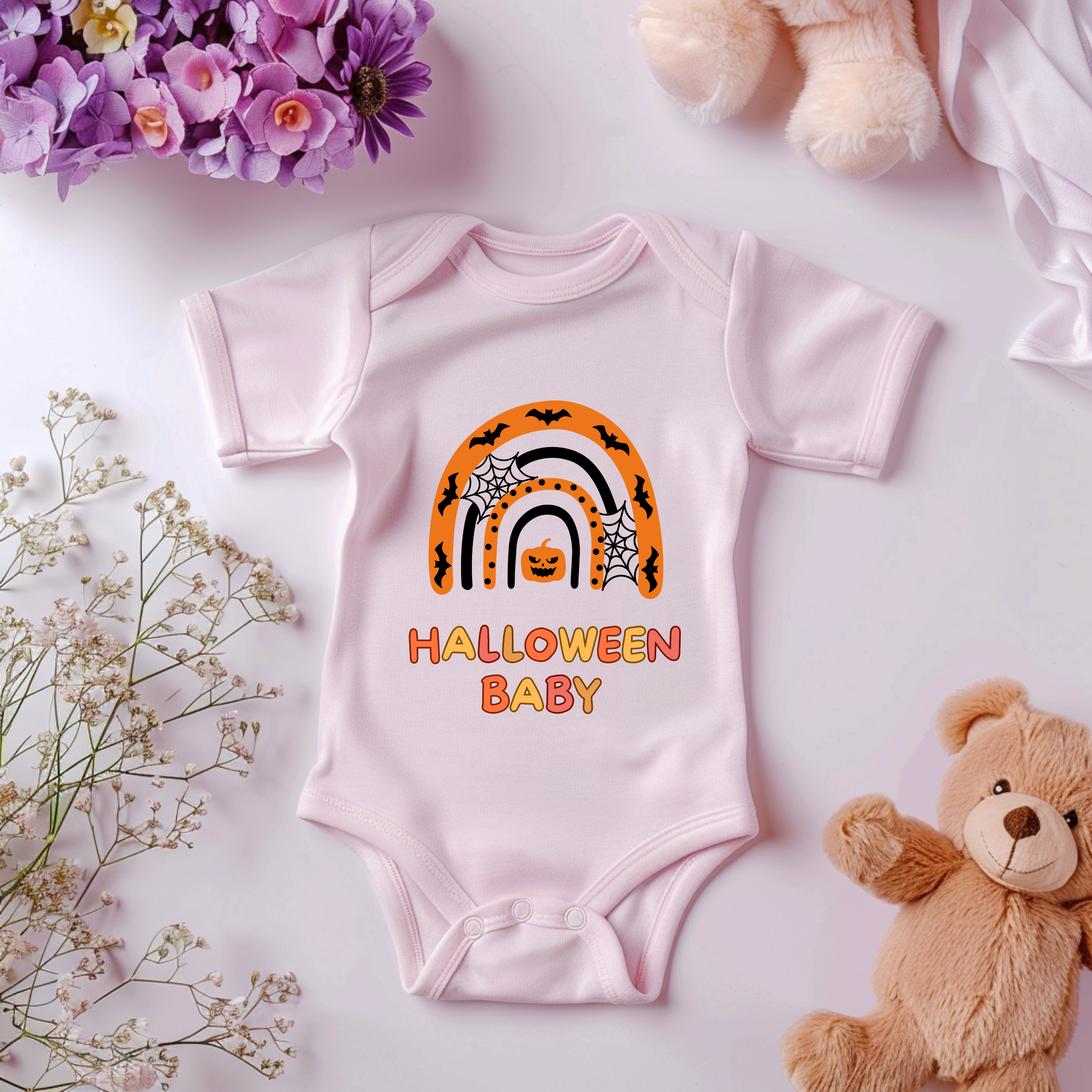 Rosa Baby-Strampler mit Halloween-Motiv: bunter Regenbogen in Orange- und Schwarztönen, darunter der Schriftzug ‚Halloween Baby‘.