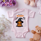 Rosa Baby-Strampler mit Halloween-Motiv: niedlicher Kürbis im Hexenkostüm mit Hut und Umhang, umgeben von Fledermäusen. Darüber der Schriftzug ‚My First Halloween‘.