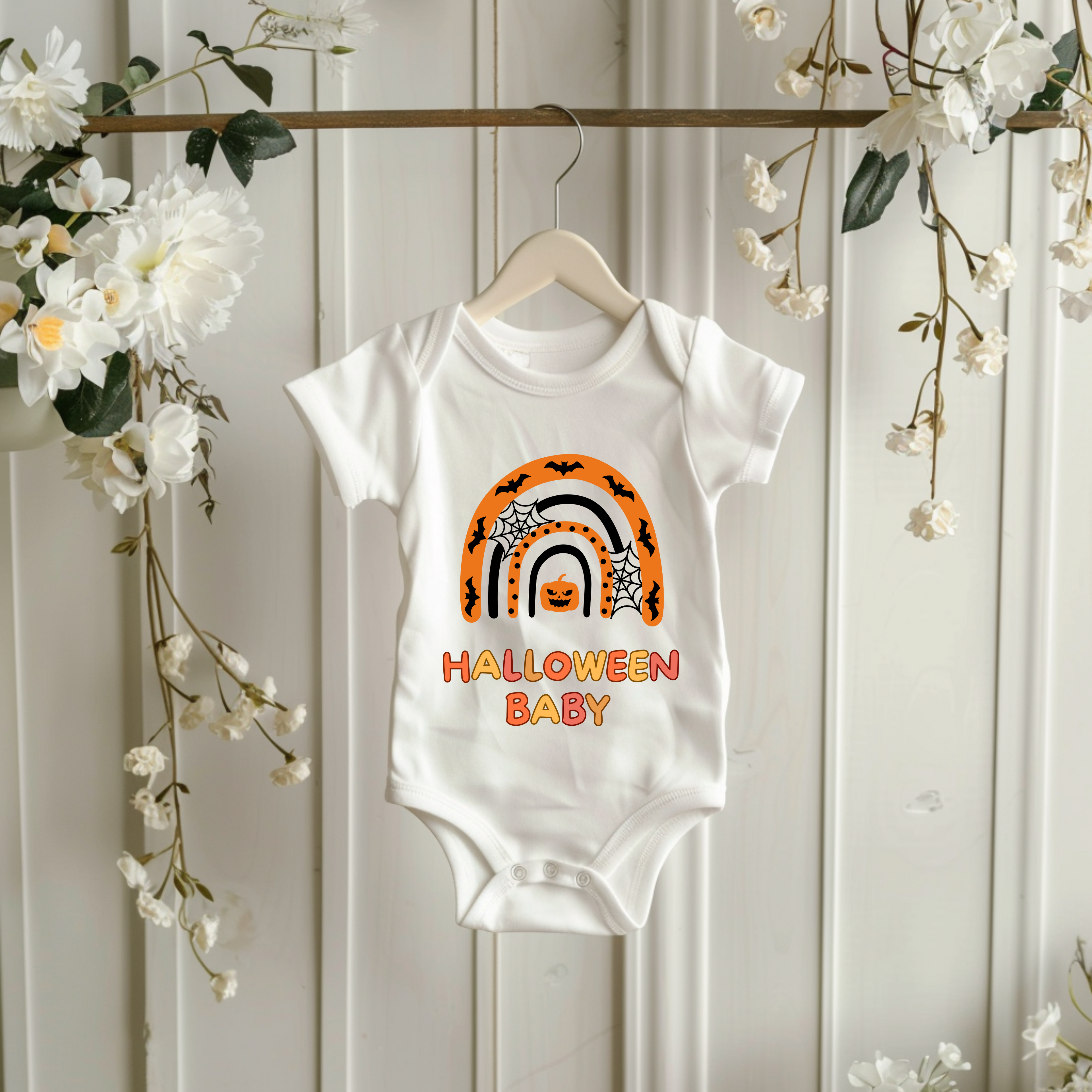 Weißer Baby-Strampler mit Halloween-Motiv: bunter Regenbogen in Orange- und Schwarztönen, darunter der Schriftzug ‚Halloween Baby‘.